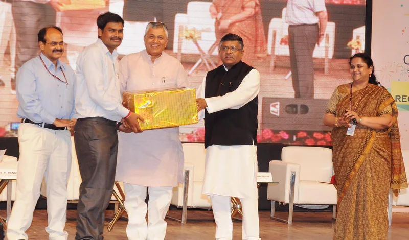 डिजिटल सेवा केंद्र कार्यक्रम के मंच पर एक केंद्र संचालक को सम्मानित करते मंत्री और अधिकारी